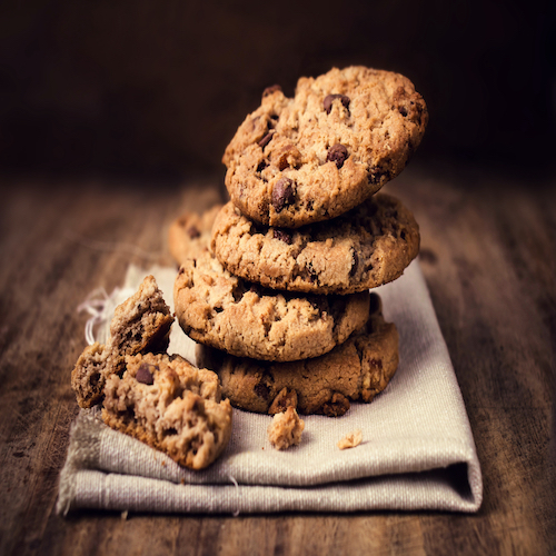 Chocolate cookies on white linen napkin on wooden table. Chocolate chip cookies shot on coffee colored cloth, closeup.
