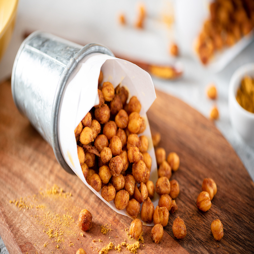 Spicy crispy roasted chickpeas with paprika, curry and hot chili pepper, selective focus. Tasty vegetarian and vegan chickpea snack.