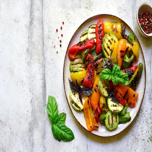 Grilled colorful vegetable : bell pepper, zucchini, eggplant on a plate over light grey slate, stone or concrete background. Top view with copy space.