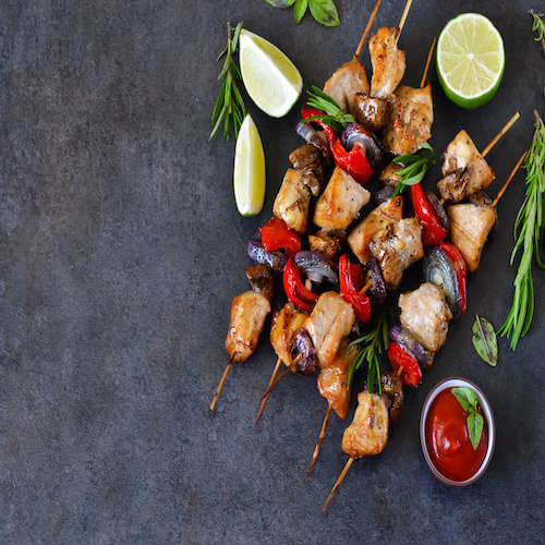 Chicken kebab on skewers with mushrooms and peppers and barbecue sauce on a black background. Food for a picnic.