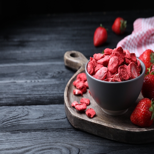 Freeze dried and fresh strawberries on black wooden table. Space for text