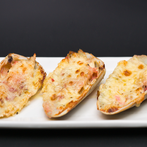 (machas a la parmesana) seashell cooked in parmesan. served on a white plate