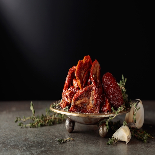 Sun-dried tomatoes in olive oil on a stone table. Copy space.