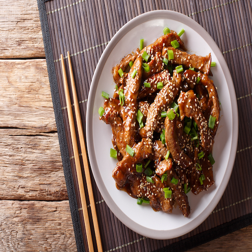 Traditional Asian beef teriyaki with green onions and sesame close-up on a plate on the table. horizontal top view from above