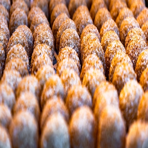 Detail of an assortment of sweet golden coconut cookie panellets toasted on a tray fresh from the gourmet artisan oven. Typical artisan pastries, cakes and sweets from Catalonia.