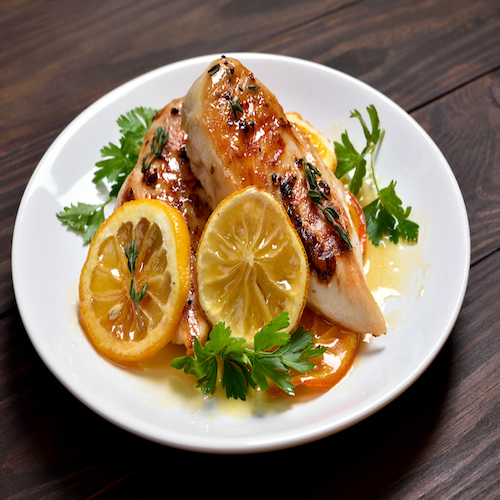 Cooked chicken breast with orange sauce on wooden table