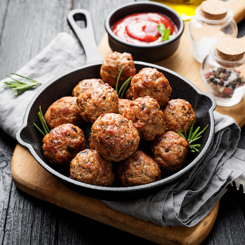 Meatballs served with tomato sauce in frying pan .