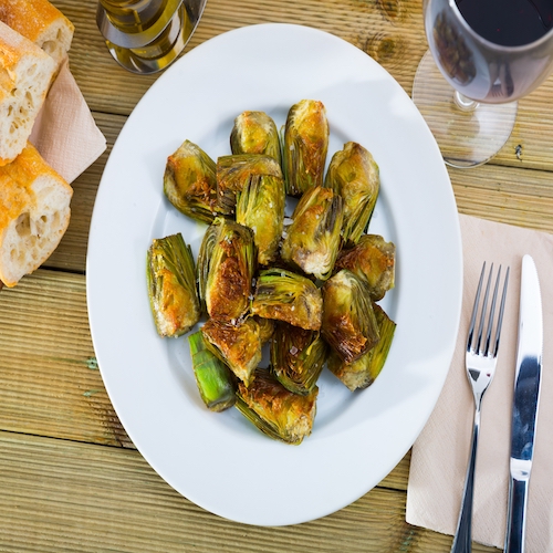 Appetizing roasted in oil artichokes served on plate
