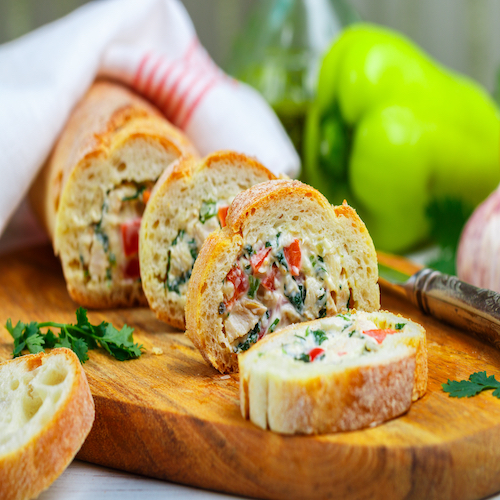 Baguette stuffed with a salad of baked chicken, cheese and fresh vegetables-bell pepper, tomato, garlic, parsley. Delicious homemade appetizer for gourmets. Selective focus