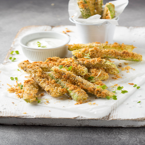 Zucchini sticks in breadcrumbs, with cheese, herbs, breadcrumbs and white yogurt sauce. Healthy tasty snack, summer food