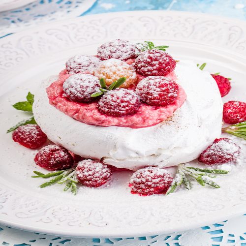 Meringue pavlova cake with whipped cream and fresh raspberries.